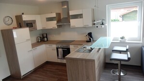 A modern kitchen with white cabinets, a built-in oven, a coffee maker, and a window with a view of the outside. - TOP!!! Headquarters u. quiet location, modern DHH, garden, 5 * level, WiFi, bicycles (Horumersiel)