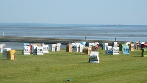 A grassy field with numbered mailboxes in various colors, a body of water in the background, and a distant city skyline. - TOP!!! Headquarters u. quiet location, modern DHH, garden, 5 * level, WiFi, bicycles (Horumersiel)