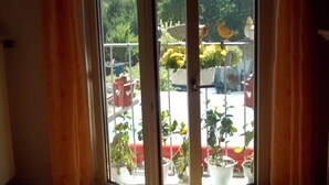 A room with a large window overlooking a balcony with potted plants and a red chair. - Curr. M.Flair, quiet location, grGarten directly to Forest / Grassland, gr. Lake at 2km, (Blankenheim-Reetz)