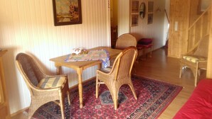 A cozy room with a wooden ceiling, a dining table with chairs, a patterned rug, and a painting on the wall. - Curr. M.Flair, quiet location, grGarten directly to Forest / Grassland, gr. Lake at 2km, (Blankenheim-Reetz)