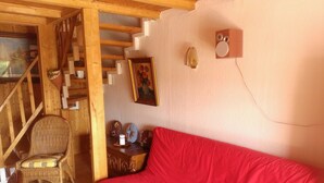 A cozy room with a red sofa, wicker chairs, a wooden staircase, and a painting on the wall. - Curr. M.Flair, quiet location, grGarten directly to Forest / Grassland, gr. Lake at 2km, (Blankenheim-Reetz)
