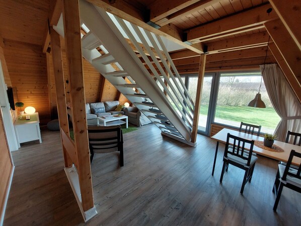 Un acogedor loft con escalera de madera, zona de comedor y un conjunto de sofás.