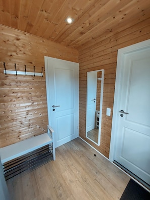 Ein Zimmer mit Holzwänden und Holzböden, weißen Türen, einer Bank und einem Spiegel.