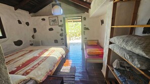 Une chambre rustique avec deux lits, un plancher en bois et un mur en pierre.