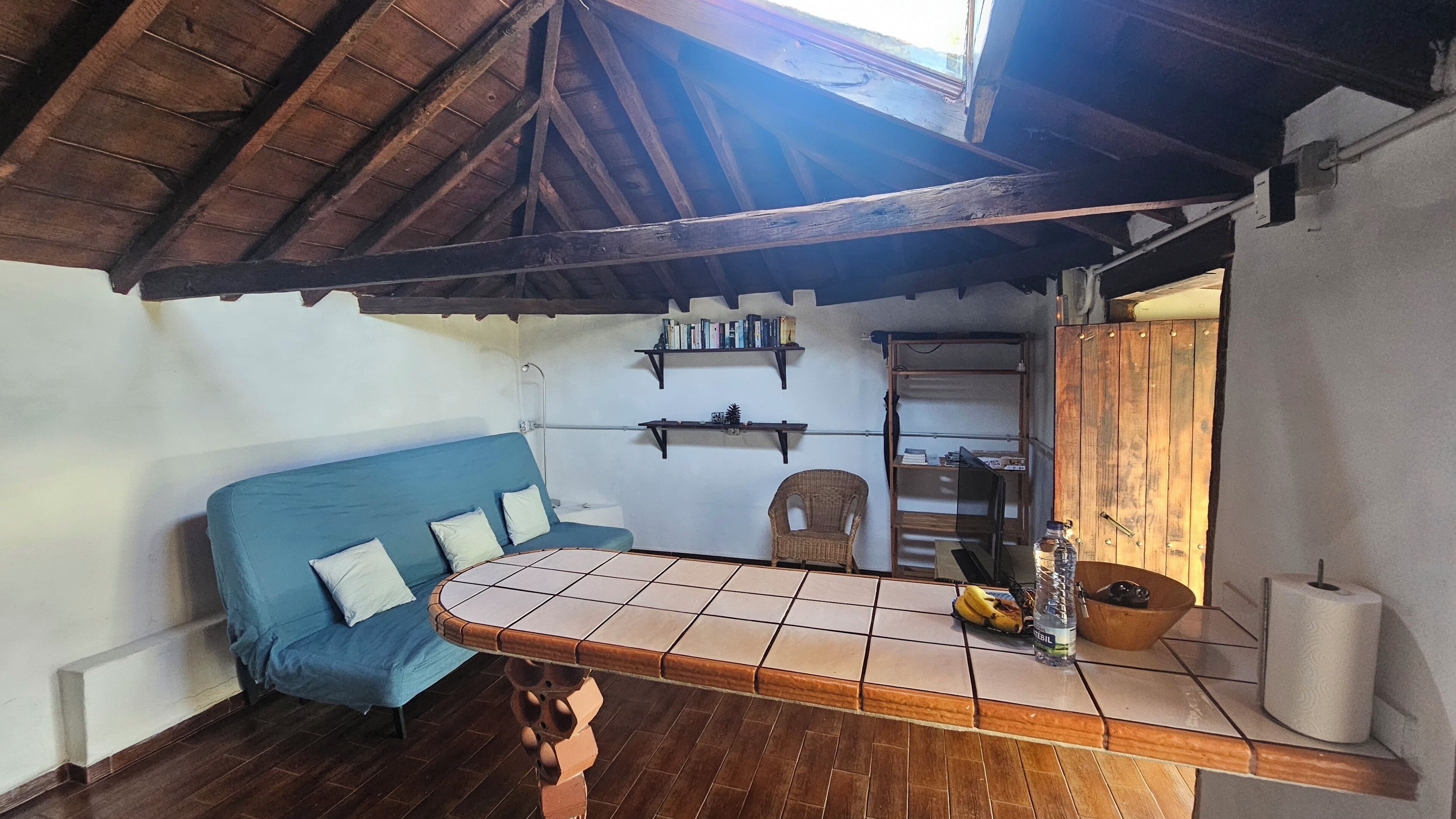 Een gezellige kamer met een blauwe bank, een houten tafel en een betegelde vloer.