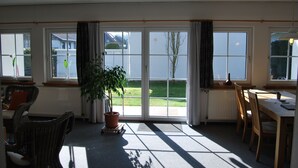 A room with a large sliding glass door leading to a garden, wicker furniture, and a potted plant. - Just go on vacation. Vacation apartment 2-4 pers. 65sqm, terrace, 2 bedrooms. W-lan (Walkenried)