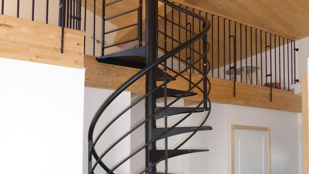 Eine moderne Wendeltreppe mit Holzboden und einer weißen Tür im Hintergrund.