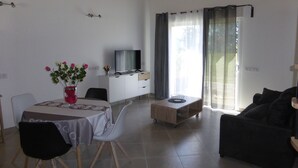 Ein modernes Wohnzimmer mit Essbereich, einem Flachbildfernseher, einem Couchtisch und einer Couch.