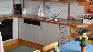 Una cocina compacta con lavavajillas, cafetera y fregadero.