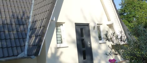 Una casa con un tejado empinado, un ventanal pequeño y una puerta.