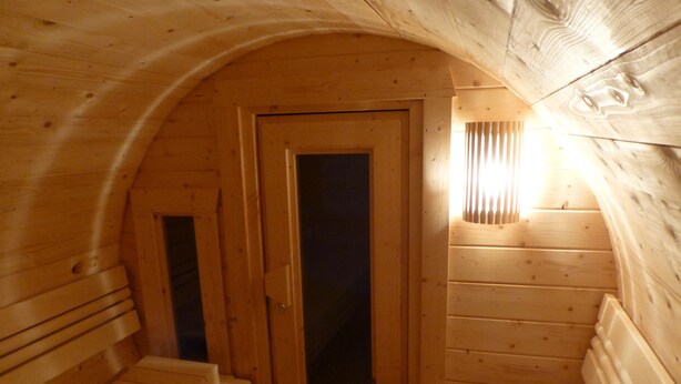 A wooden sauna room with benches and a door. - Holiday house of high quality and cozy, sauna, 150m to the beach, quiet natural location (Rankwitz (OT Quilitz))
