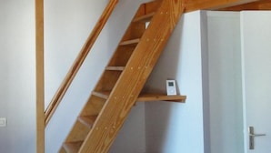 A wooden staircase with a landing area, a door, and a small shelf with an electronic device.