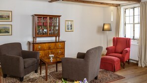 Un salon avec deux fauteuils, un meuble en bois et une lampe sur pied.