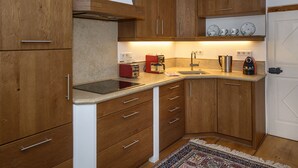 Une cuisine compacte avec des meubles en bois, une cuisinière encastrée et une machine à café.