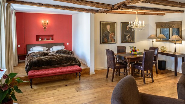 Une chambre à coucher avec un grand lit, une table à manger avec des chaises et un lustre.