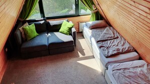 A cozy room with a sofa, a bed, and a window with curtains. - Family-friendly holiday house with large garden and great features (Butjadingen-Burhave)