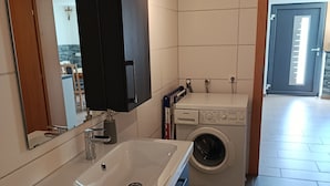 A bathroom with a sink, mirror, dark cabinet, and a washing machine. - Guesthouse Michael in Navis am Brenner - Valley of Love (Navis)