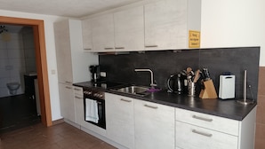 A modern kitchen with white cabinets, a black countertop, a coffee maker, a kettle, and a knife block. - Guesthouse Michael in Navis am Brenner - Valley of Love (Navis)