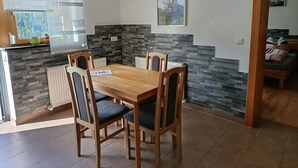 A dining area with a wooden table and chairs, a cross on the wall, and a painting above the table. - Guesthouse Michael in Navis am Brenner - Valley of Love (Navis)