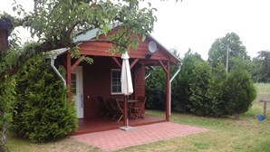 A wooden cabin with a covered porch, a dining table with chairs, and a satellite dish.