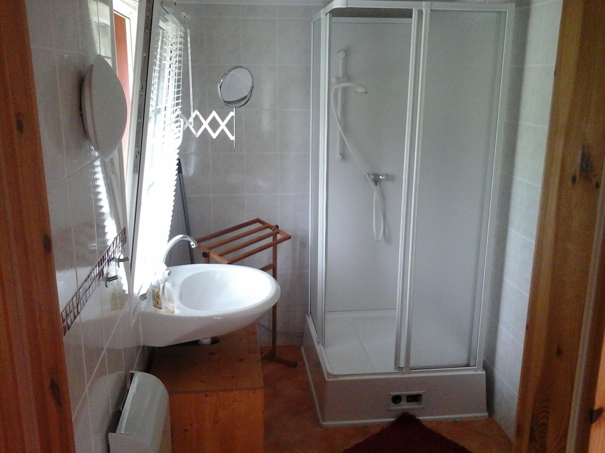 Een badkamer met een witte wastafel, een spiegel en een douchecabine.