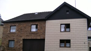 A two-story house with a stone facade and a white upper section. - Holiday in a quiet location (Nideggen)