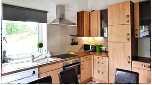 A compact kitchen with wooden cabinets, a stainless steel range hood, a microwave, and a sink.