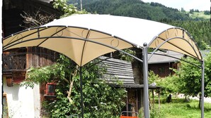 An outdoor patio with a table and chairs, a covered seating area, and a potted plant.