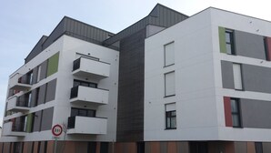 A multi-story residential building with balconies, a no parking sign, and a height restriction sign.