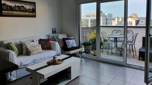 A modern living room with a white sofa, a coffee table, and a cityscape painting on the wall.