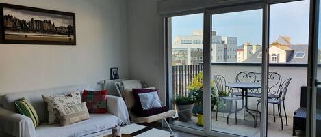 Una sala de estar moderna con un sofá blanco, una mesita de centro y un cuadro de un paisaje urbano en la pared.