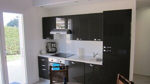 A modern kitchen with black cabinets, a stainless steel sink, and a dining table with a bottle of wine. - Cosy studio 2 pers.,  parking,  2 terraces,  wifi (Laroque-Des-Albères)