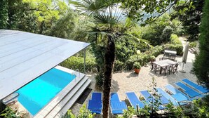Ein Poolbereich mit freiem Blick auf den Pool, Liegestühle und umliegendes Grün.