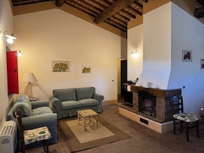 Ein gemütliches Wohnzimmer mit Kamin, einer Couch, einem kleinen Tisch und einer Lampe.