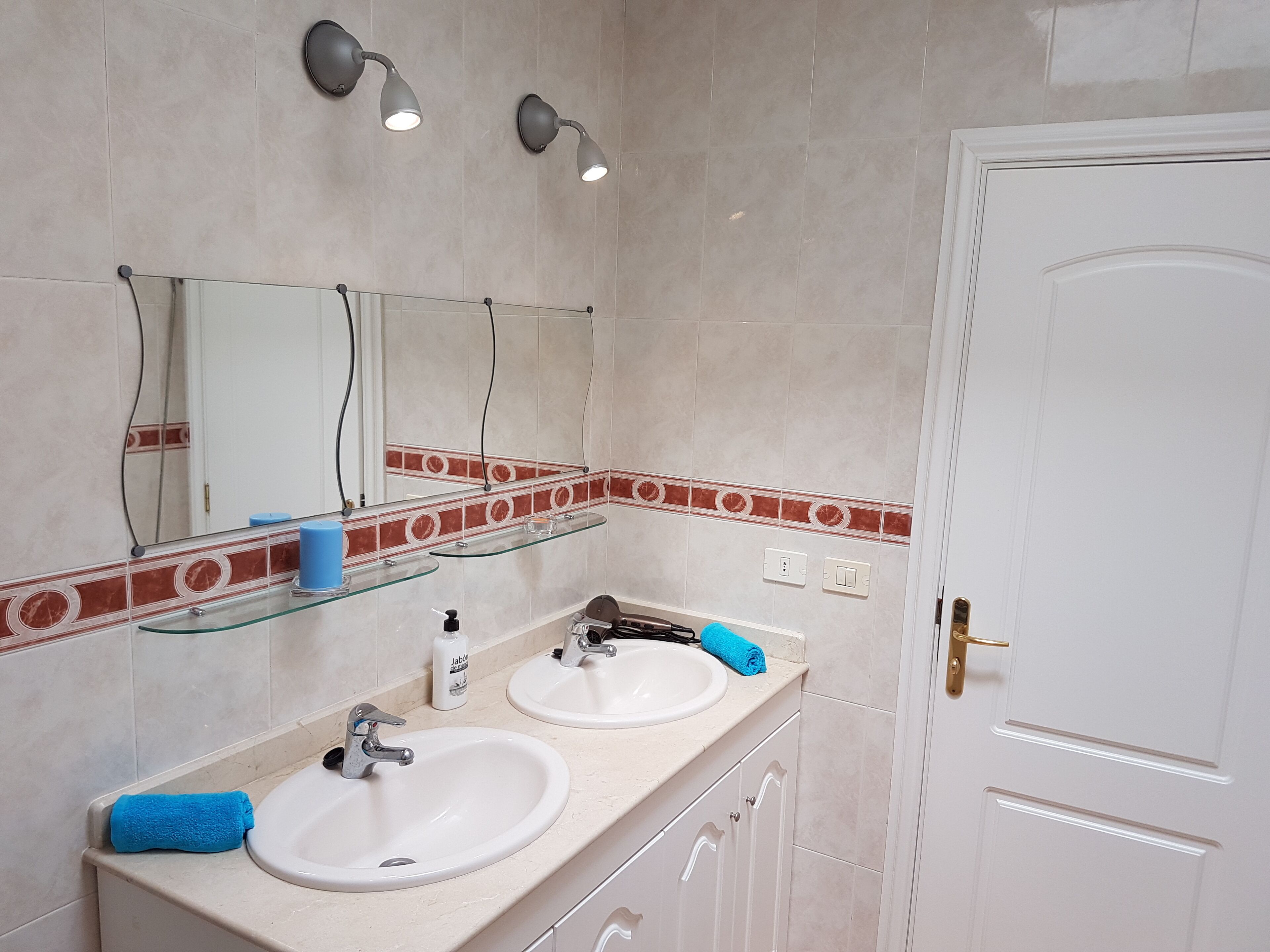 A bathroom with two sinks, a mirror, and a door.