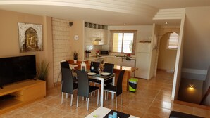 A modern living room with a TV, dining area, kitchen, and a staircase leading to another level. - Villa Roque del Conde 3 with fantastic sea view, Terrace, Pool, Wifi, SAT-TV (Costa Adeje)