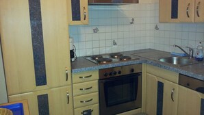 A kitchen with beige cabinets, a stove, an oven, and a sink. - Apartment city center (Wien)