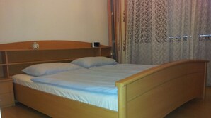 A single bed with a wooden frame and a headboard, a bedside table, and a curtain with a floral pattern. - Apartment city center (Wien)