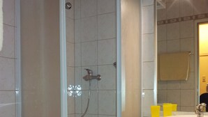 A bathroom with a shower enclosure, a sink, and a mirror. - Apartment city center (Wien)
