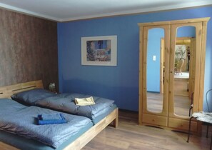 Ein Schlafzimmer mit zwei Betten, einem Holzschrank und einem gerahmten Bild an der Wand.
