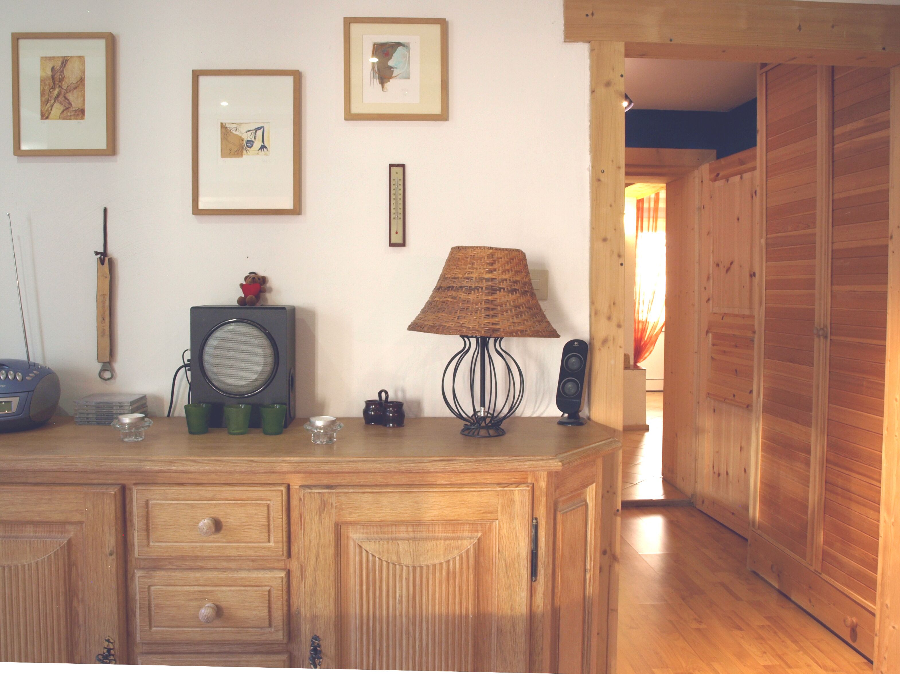 Ein Holzkapuzenbad mit Schubladen, ein Radio, eine Lampe und gerahmte Bilder an der Wand.
