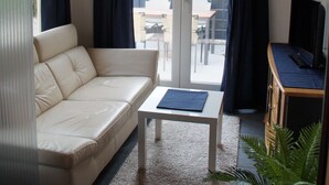 A living room with a sofa, a coffee table, and a TV on a wooden stand.