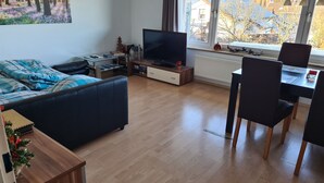 Un salon moderne comprenant un canapé, un téléviseur, une table à manger et des chaises.