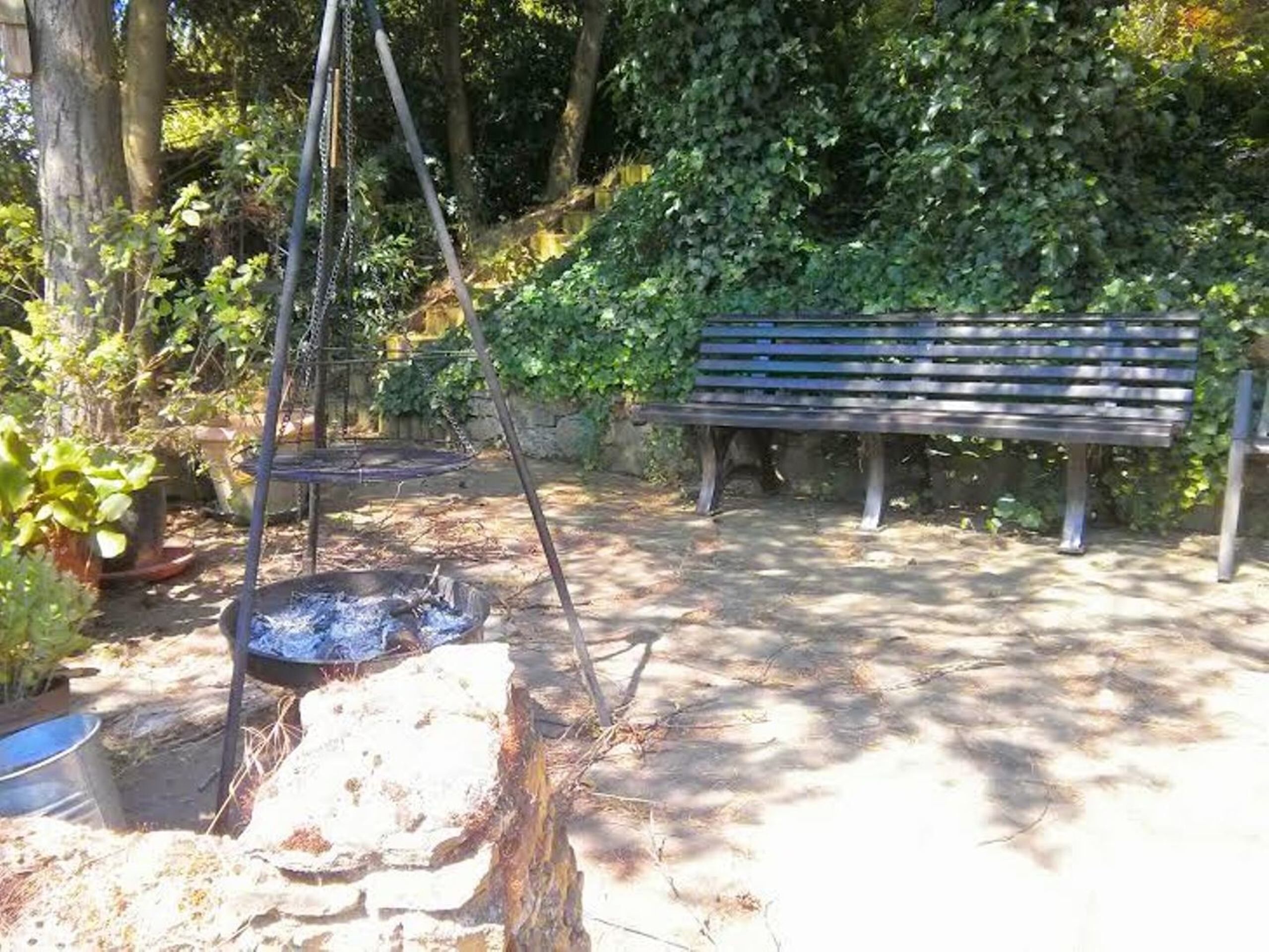 Ein Park mit einer Holzbank, einer Feuerstelle und einer Schaukel.