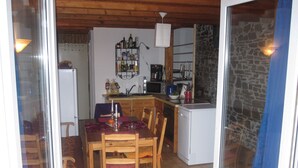 A compact kitchen with wooden cabinets, a refrigerator, a microwave, and a small sink. - Apartment with flair, quiet location, large garden directly at forest / meadow, large swimming lake at 2km, (Blankenheim-Reetz)