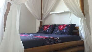 A bed with a canopy, wooden beams, and a floral bedspread. - Villa Bois Jolan in Saint-Anne, Guadeloupe (Sainte-Anne)