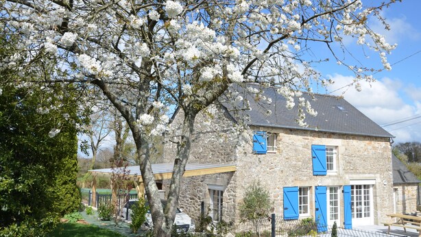 A stone building with blue shutters, surrounded by a garden with blooming trees. - Gîte de la Bézardais for 4 people in Dinan, Brittany, France. (Quévert)