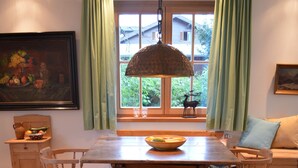 A wooden dining table with chairs, a hanging lamp, and a window with curtains. - Family-friendly modern country house (Zell am See)