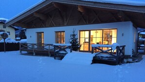 A snow-covered building with a wooden facade and large windows. - Family-friendly modern country house (Zell am See)
