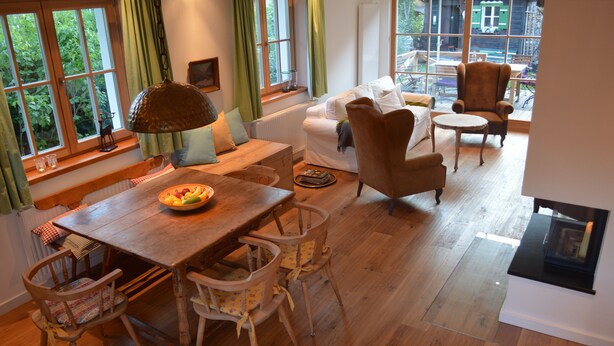 A cozy living room with a wooden table, chairs, a sofa, and a fireplace. - Family-friendly modern country house (Zell am See)